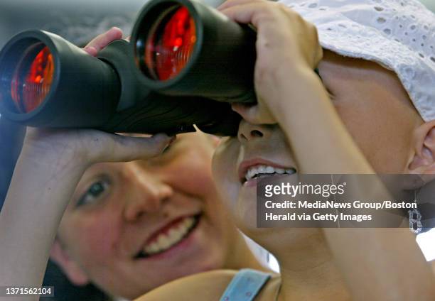 Leukemia patient Payton Randall of Plymouth, looks through a pair of binoculars while sitting on the lap of her aunt Ashley Lyne moments before...