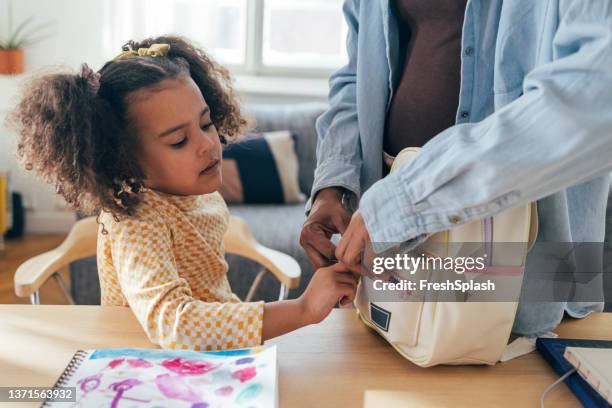 an unrecognizable african-american woman helping her cute little daughter to pack her schoolbag - skolväska bildbanksfoton och bilder