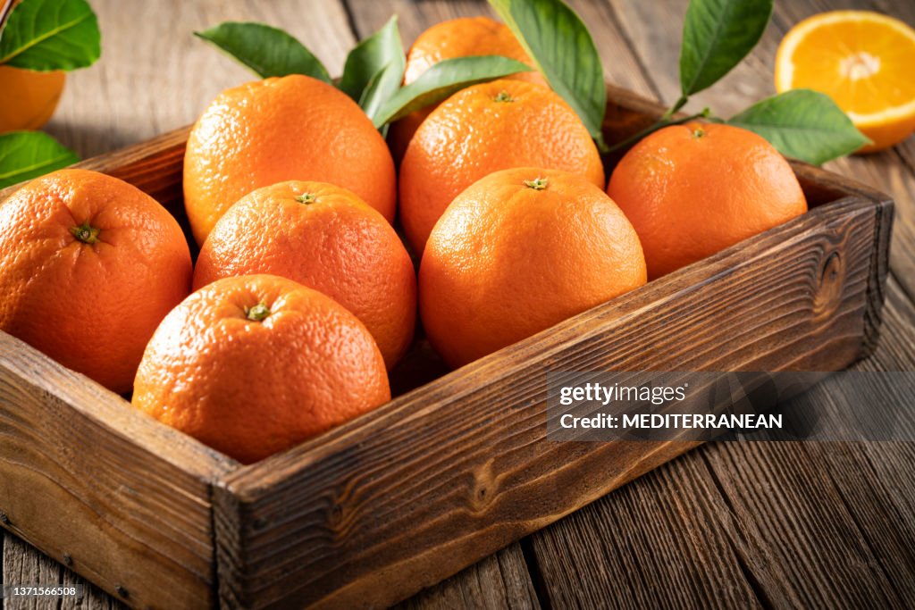 Caja de madera de frutos de naranja en cosecha con hojas de naranjo frescas