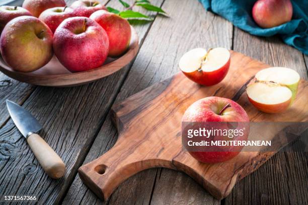 red apple fuji closeup wet with dew drops on cutting board and knife on wooden table - gala apple stock pictures, royalty-free photos & images