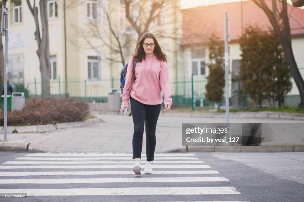 A teenage girl (16-17 years) crossing the street