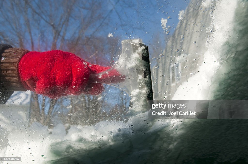 Scraping icy windshield in winter
