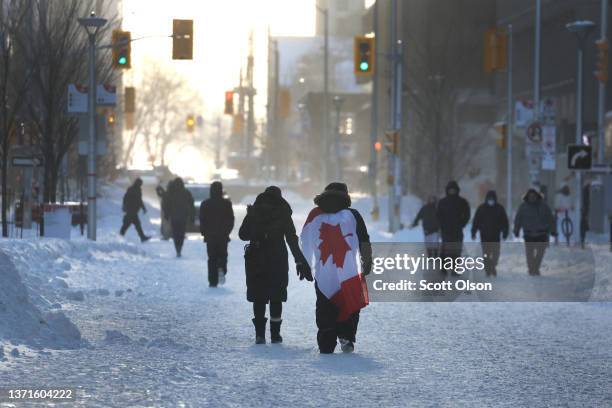 People walk near Parliament Hill where earlier in the day police moved in and ended a demonstration organized by truck drivers opposing vaccine...