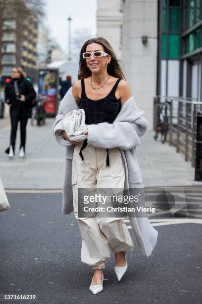 Guest is seen wearing grey oversized coat, Bottega Veneta bag, creme white bag with pockets, Prada heels outside Nensi Dojaka during London Fashion...