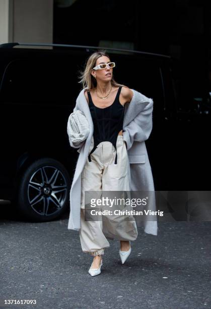 Guest is seen wearing grey oversized coat, Bottega Veneta bag, creme white bag with pockets, heelsoutside Nensi Dojaka during London Fashion Week...