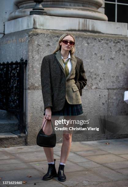 Guest is seen wearing two tone blazer in brown grey, tie, checkered mini skirt, black bag outside Rixo during London Fashion Week February 2022 on...