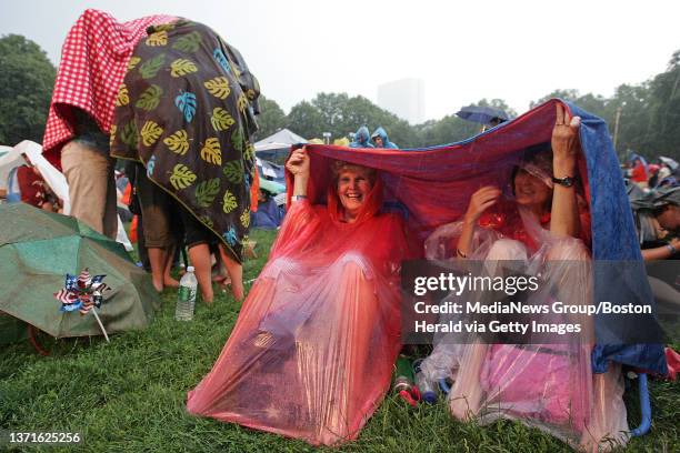 Gale and Susan Porr, take shelter under a tarp from the rain at the rehersal concert for the forth of july concert at the hatch shell. Thursday, July...