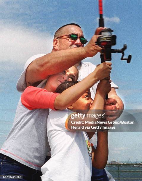 Scott Dalrymple helps Samanthe Dejesus and Ashley Santana cast their line at a Parks Dept sponsored fishing trip to the Fishing Pier on Castle Island.