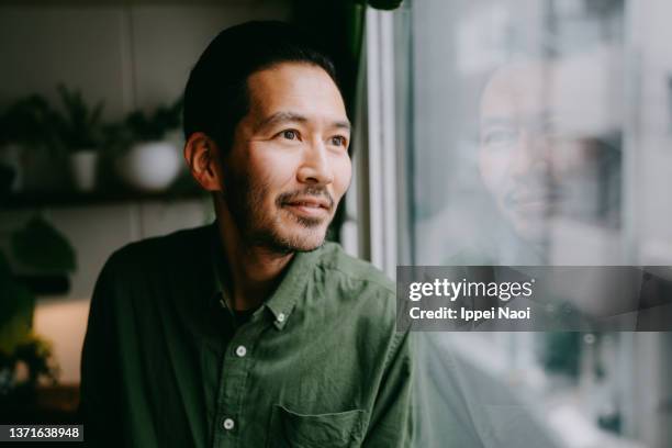 man looking outside from window - portrait candid ストックフォトと画像