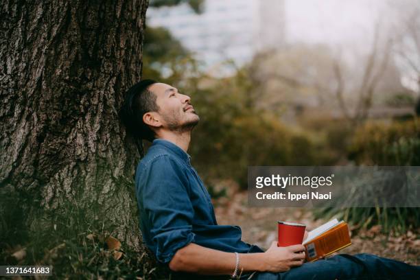 man having a coffee break at park in city, tokyo - cómoda fotografías e imágenes de stock