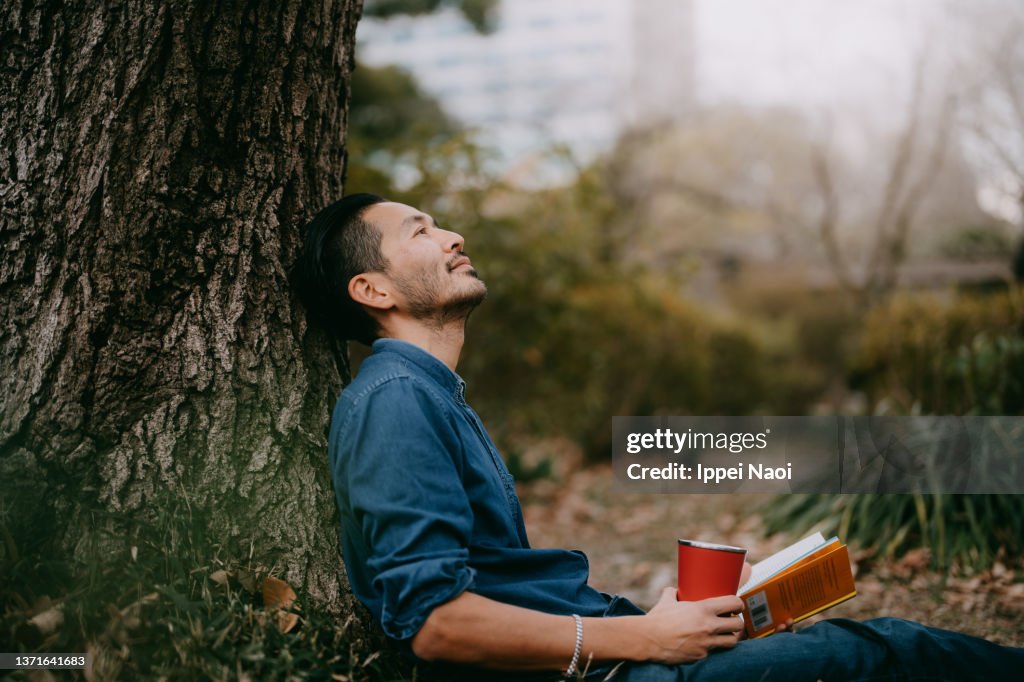 Man having a coffee break at park in city, Tokyo