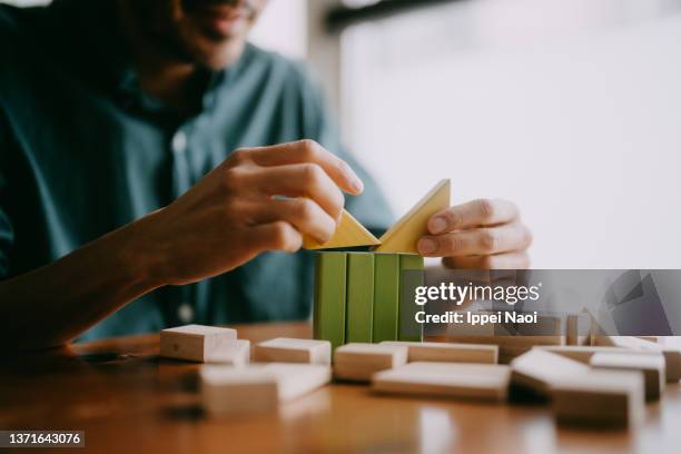 man playing with wooden blocks on table - building block stock-fotos und bilder