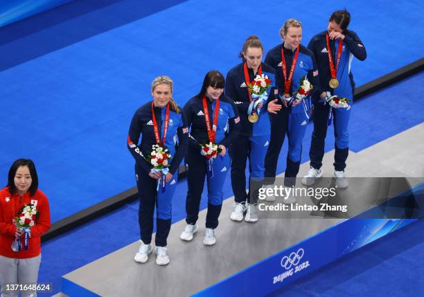 Satsuki Fujisawa of Team Japan looks on as gold medal winners Milli Smith, Hailey Duff, Jennifer Dodds, Vicky Wright and Eve Muirhead of Team Great...