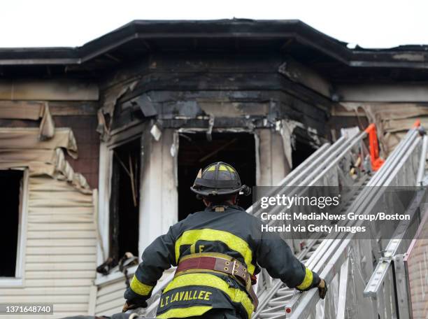 Lawrence firefighter surveys the damage while climbing a ladder truck at the scene of a three-alarm fire that ripped through a triple-decker...