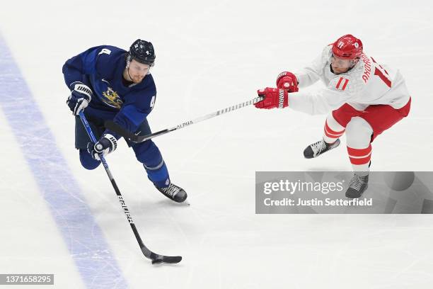 Mikko Lehtonen of Team Finland skates with the puck as Sergei Andronov of Team ROC defends in the second period during the Men's Ice Hockey Gold...