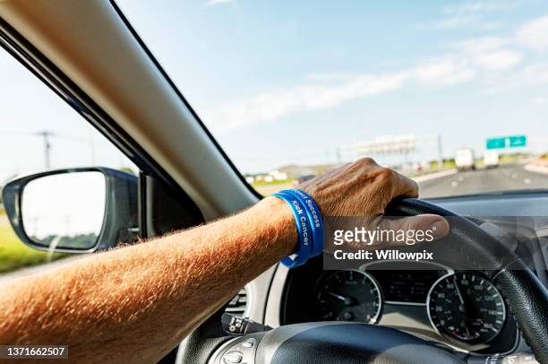 autofahrer trägt krebsarmband - point of view driving stock-fotos und bilder
