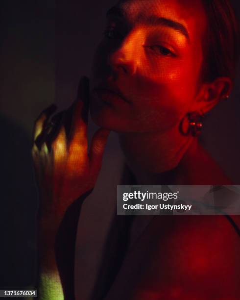 young beautiful woman in red light indoors - face projection stock pictures, royalty-free photos & images