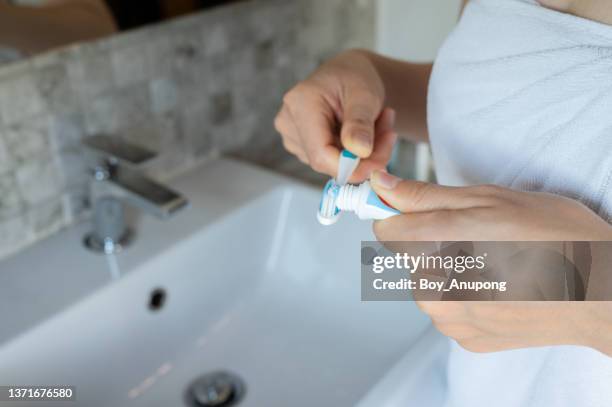 close up of woman squeezing toothpaste on toothbrush for brushing her teeth. - fluor stockfoto's en -beelden