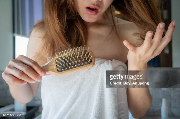 close-up of worried woman holding comb with hair loss after brushing her hair. - human hair stock pictures, royalty-free photos & images