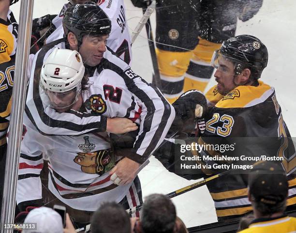 Referee Pierre Racicot holds back Chicago Blackhawks defenseman Duncan Keith from getting hit by Boston Bruins center Chris Kelly in the first period...