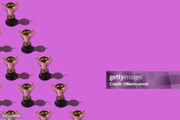 winner gold cups trophy pattern with hard shadow, on the left side, on purple background. winner victory and feminism concept - awards ceremony trophy stock pictures, royalty-free photos & images