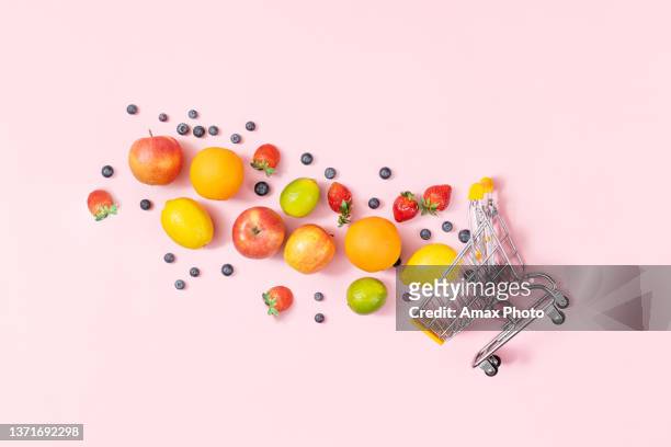 shopping trolley with fruits on pink background, table top view - shopping basket stock pictures, royalty-free photos & images
