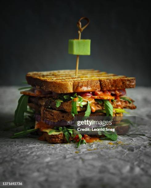 layered sandwich with toasted bread, bacon, cheese and tomato sauce on gray background - sanduíche club - fotografias e filmes do acervo