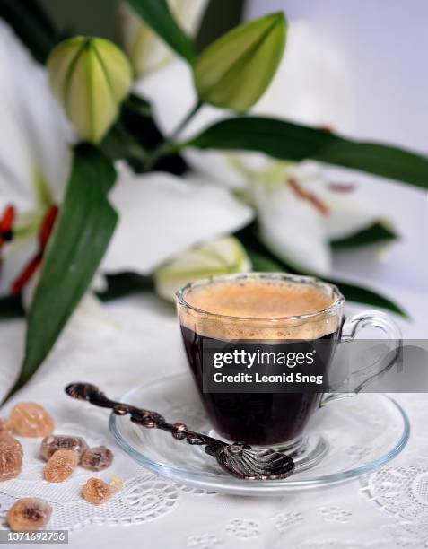little glass cup of black coffee side view on blurred flower background closeup. selective focus - americano photos et images de collection