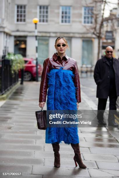 Betty Bachz seen wearing blue off shoulder dress, vinyl button shirt, suede high knee boots, bucket bag outside Huishan Zhang during London Fashion...