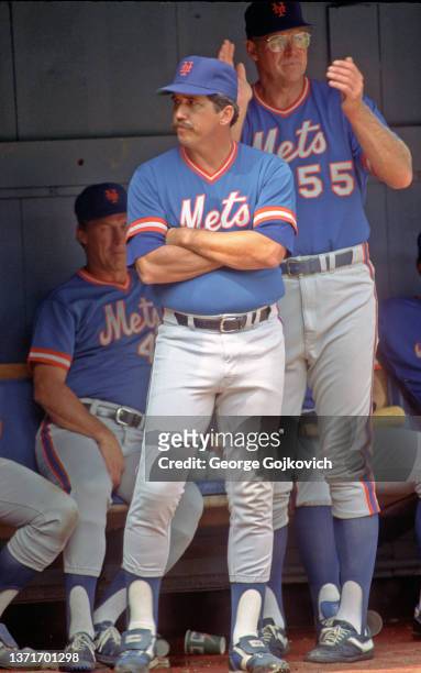 Manager Davey Johnson of the New York Mets looks on from the dugout as he stands near coach Frank Howard and pitching coach Mel Stottlemyre during a...