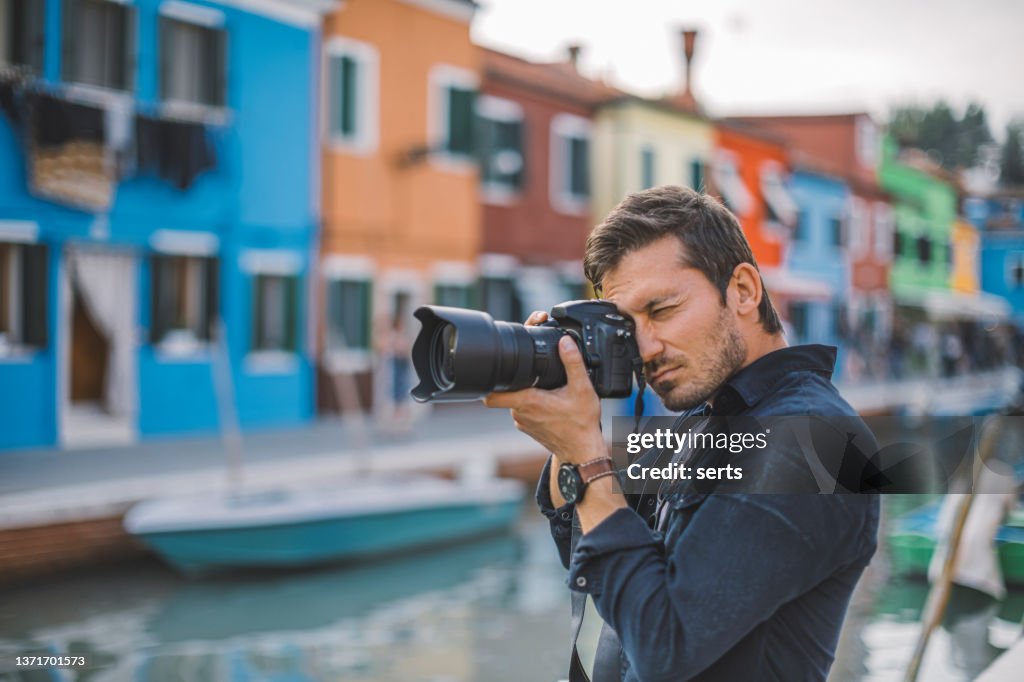 Männlicher Fotograf fotografiert bunte Häuser am Kanal in Burano Town, Venedig, Italien