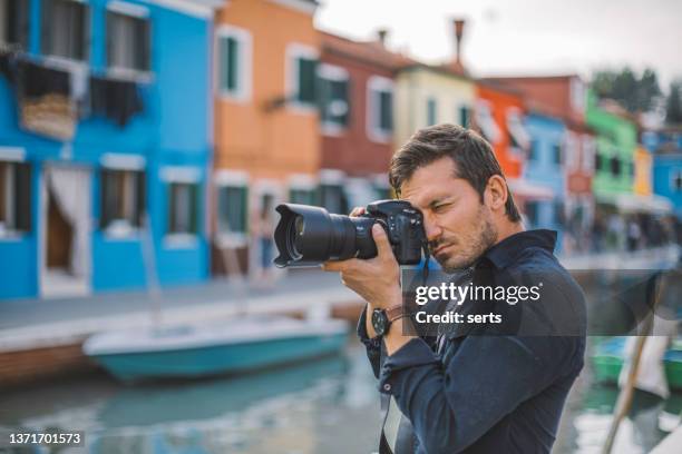 männlicher fotograf fotografiert bunte häuser am kanal in burano town, venedig, italien - kameramann stock-fotos und bilder