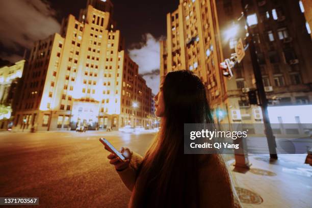 beautiful young asian woman using smartphone standing at crossroad, shanghai, china - wide angle city stock pictures, royalty-free photos & images