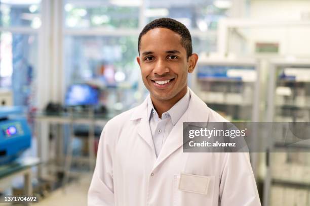 portrait of a confident male scientist standing in a medical laboratory - black lab stockfoto's en -beelden