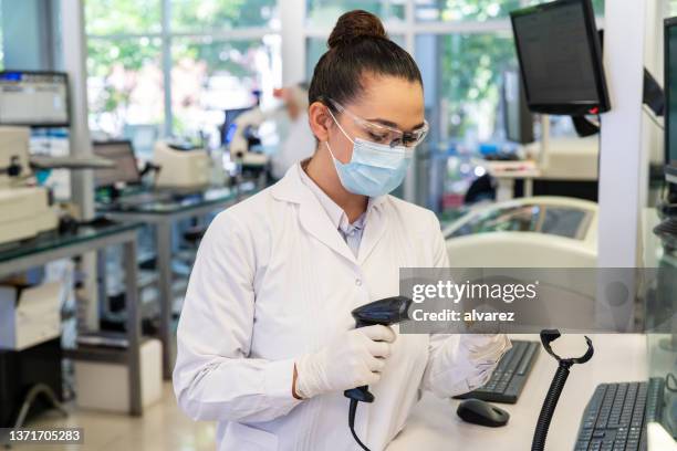 wissenschaftler scannt medizinisches probenreagenzglas mit barcode-scanner im labor - data collection stock-fotos und bilder