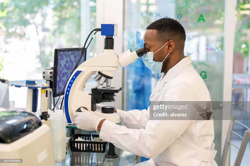 Side view of a medical researcher looking through a microscope
