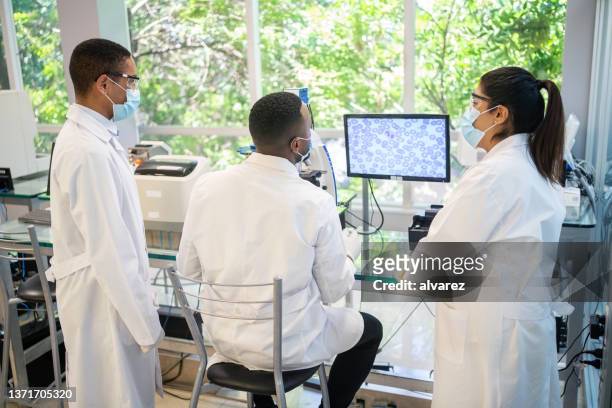 trois scientifiques travaillant ensemble dans un laboratoire médical - pathologist photos et images de collection
