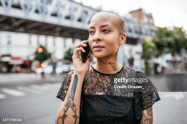 portrait of serious modern mixed race woman in the city, using smart phone for talking - sassy paris stockfoto's en -beelden