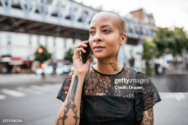 portrait of serious modern mixed race woman in the city, using smart phone for talking - sassy paris stock pictures, royalty-free photos & images