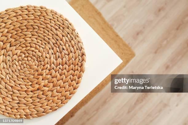 a round jute rug lies on a white table. jute fiber rug. white table. natural color. kitchen interior in light colors. eco interior. woven rug. eco rugs for the kitchen. - en osier photos et images de collection