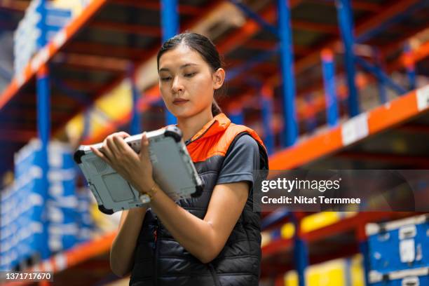 improved efficiency and productivity with a cloud based wms (warehouse management system). low angle view of a warehouse supervisor using industrial tablet to checking stock level and update by online inventory software in a large factory warehouse. - pallet industrial equipment fotografías e imágenes de stock