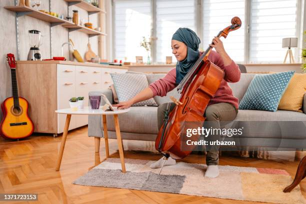jovem muçulmana assistindo um tutorial no tablet sobre como jogar violoncelo - cello - fotografias e filmes do acervo