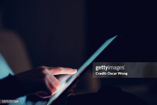 close-up of young woman using digital tablet in the dark - hand touching screen side stock pictures, royalty-free photos & images