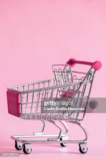 shopping cart on pink background - shopping trolleys stockfoto's en -beelden