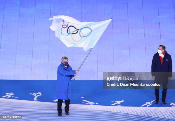 International Olympic Committee President Thomas Bach waves the flag of the IOC during the Beijing 2022 Winter Olympics Closing Ceremony on Day 16 of...