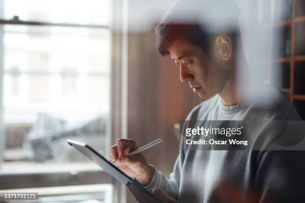 young man working from home with digital tablet - chinese home stock-fotos und bilder
