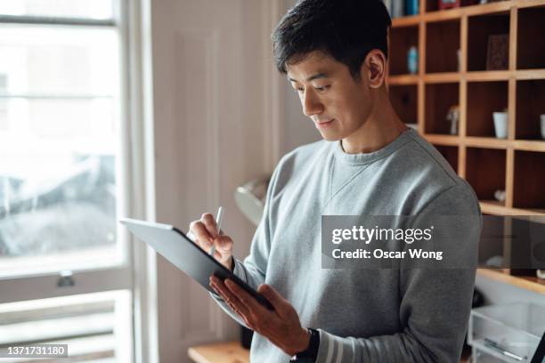 young man working from home with digital tablet - using digital tablet asian stock pictures, royalty-free photos & images