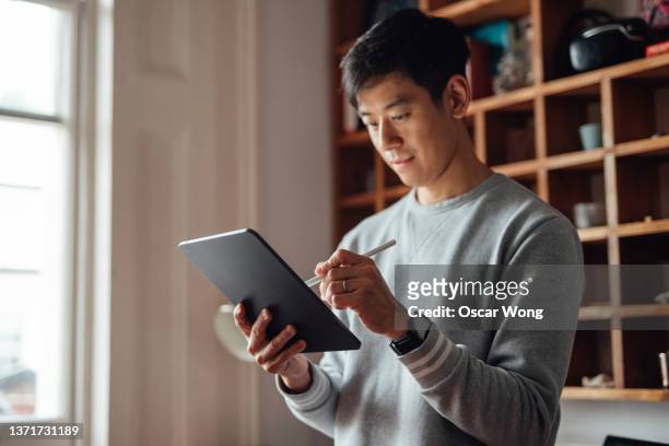young man working from home with digital tablet - creative director stock pictures, royalty-free photos & images