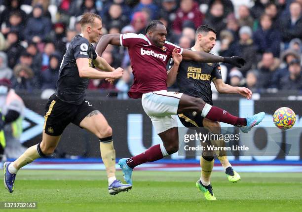 Michail Antonio of West Ham United is challenged by Emil Krafth and Fabian Schaer of Newcastle United during the Premier League match between West...