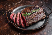 Grilled Medium Rare top sirloin beef steak or rump steak on a steel tray. Dark background. Top view